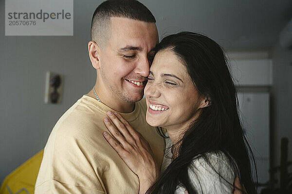 Cheerful couple embracing at home