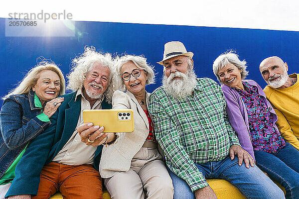 Happy elderly friends taking selfie through smart phone