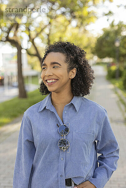 Smiling woman with curly hair standing at public park