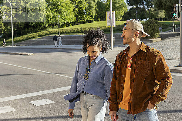 Smiling boyfriend and girlfriend crossing road on street