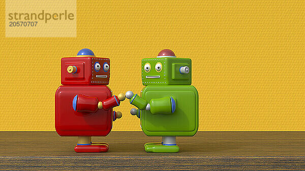 Red and green robots greeting on table in front of yellow textured wall