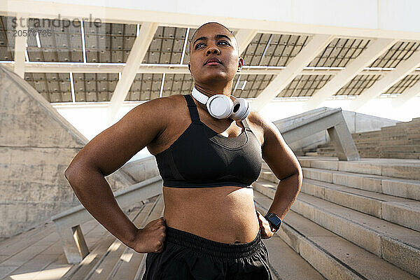 Confident sporty woman with arms akimbo on steps