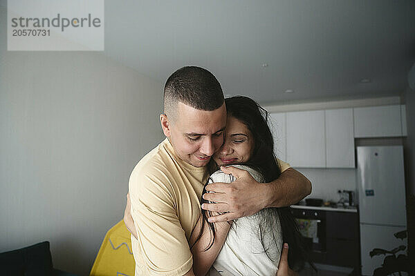 Happy man with arm around woman at home