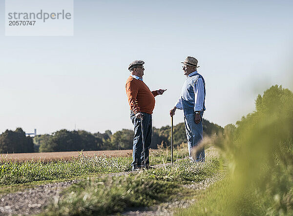 Friends talking in middle of dirt road at field