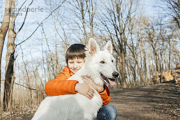 Smiling boy embracing White Swiss Shepherd Dog