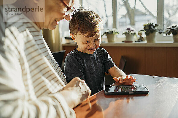 Grandmother and boy playing video game on mobile phone at home