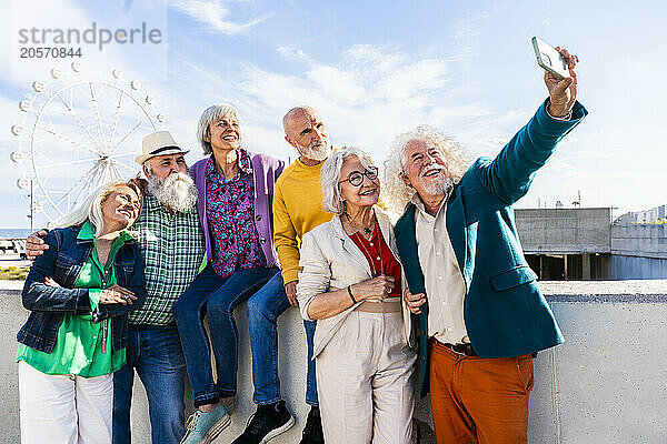 Happy man taking selfie with friends on sunny day