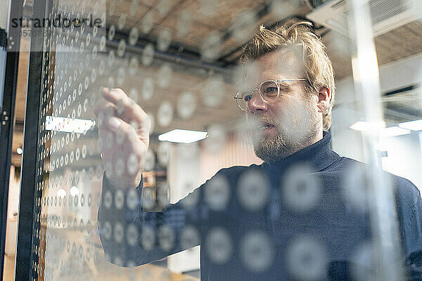 Businessman touching spotted glass in office