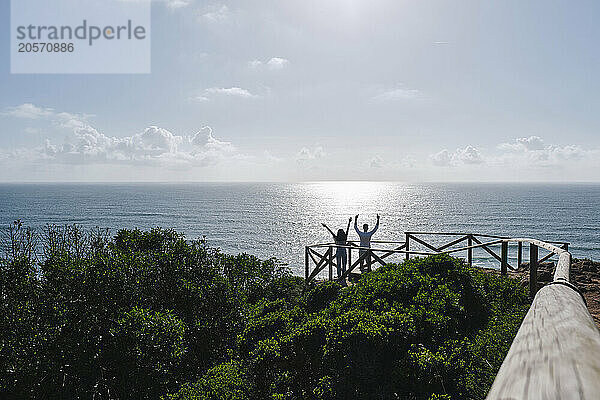 Carefree couple with arms raised standing at observation point