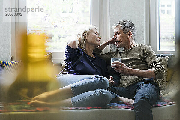 Retired senior couple sitting on alcove window seat at home