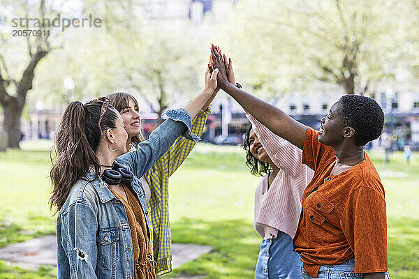 Smiling multiracial women with arms raised at park