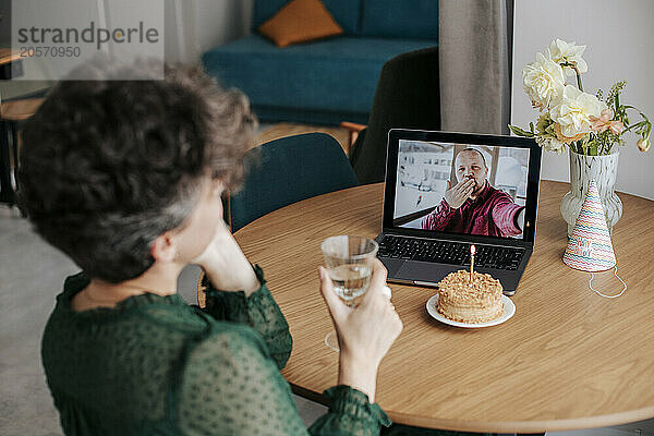 Man blowing kiss to woman through video call at home