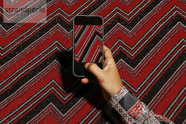 Hand of man with smartphone taking photo of abstract design