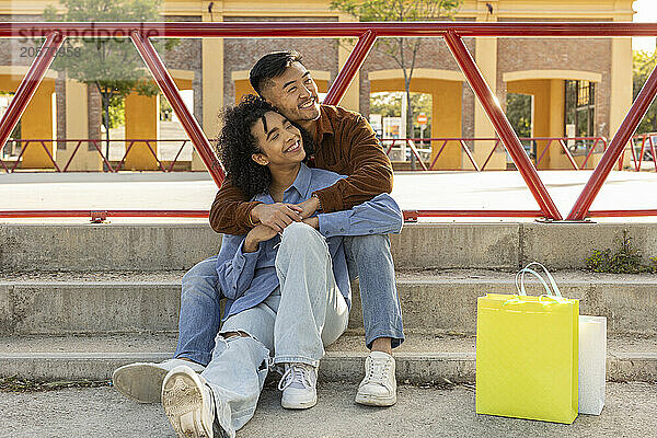 Smiling woman sitting with boyfriend on staircase at park