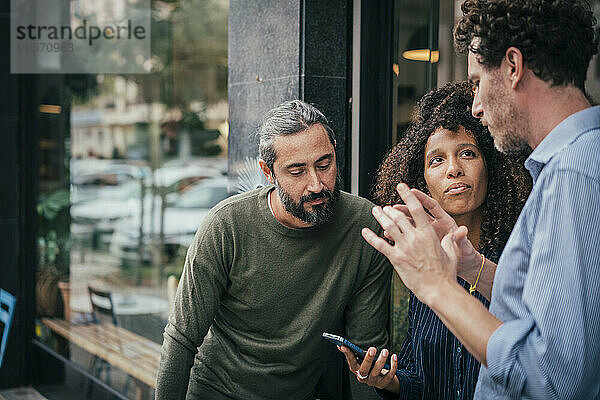 Businessman guiding colleagues standing near cafe