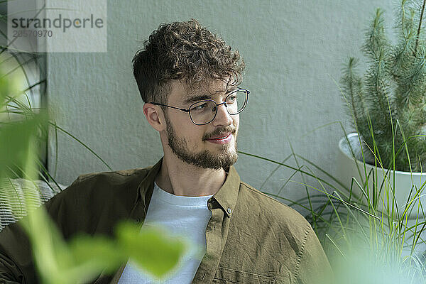 Smiling handsome young man looking away sitting in balcony