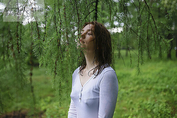 Young woman smelling tree leaves in forest