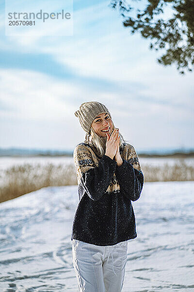 Smiling woman rubbing hands standing on snow