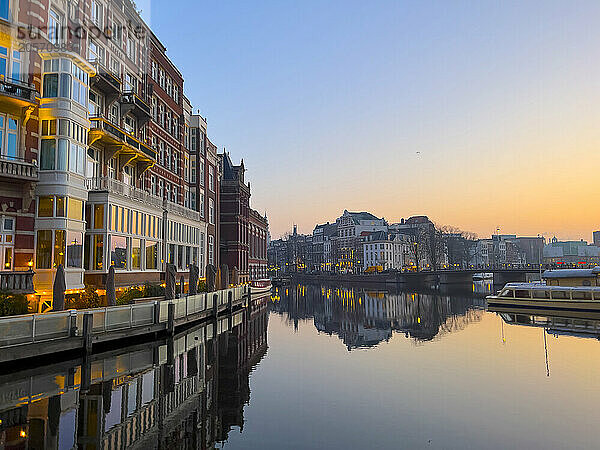 Canals of Amsterdam near residential buildings at sunrise