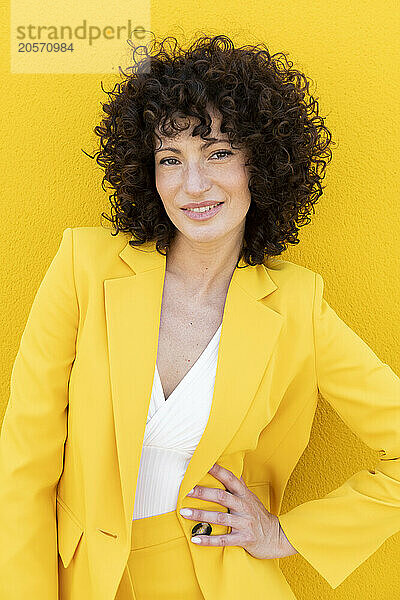 Confident woman wearing yellow blazer standing with hand on hip