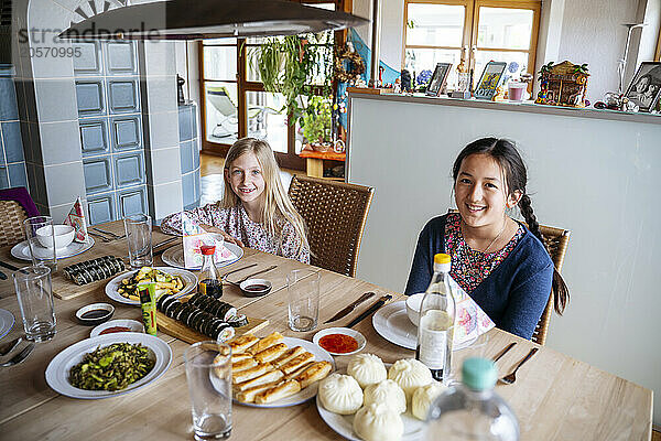 Happy girls with lunch at dining table sitting in home