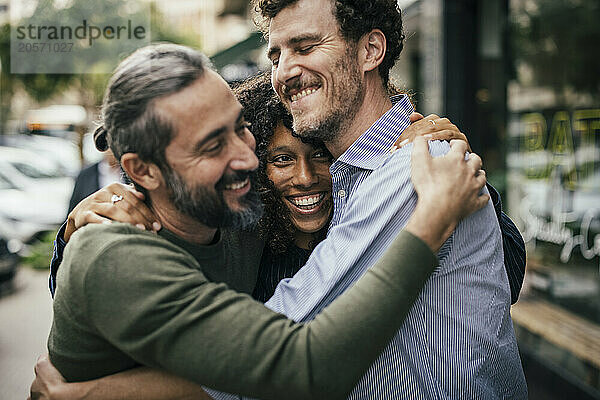 Happy friends embracing each other in front of cafe