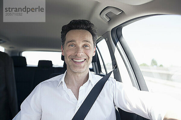 Smiling handsome mature businessman driving car