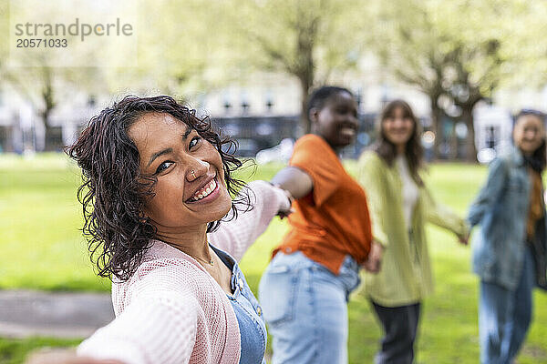 Smiling woman holding hands with friends at park