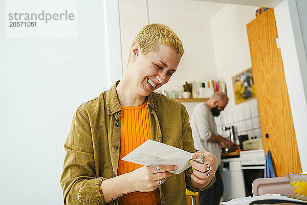 Happy freelancer holding letter envelope at home office