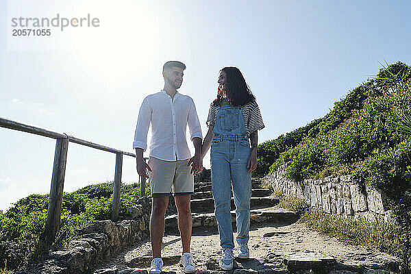 Boyfriend and girlfriend holding hands standing on steps