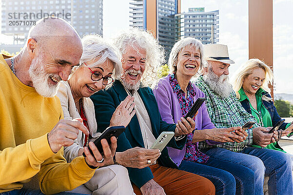 Cheerful women and men using smart phones sitting together