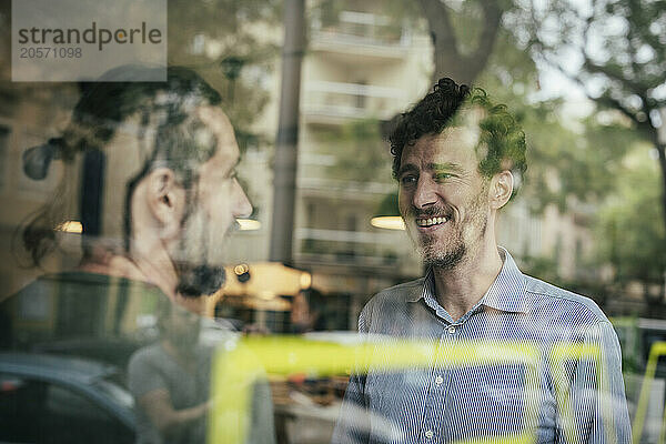 Smiling businessmen discussing at cafe