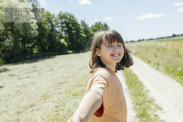 Happy girl with bangs enjoying leisure time in meadow