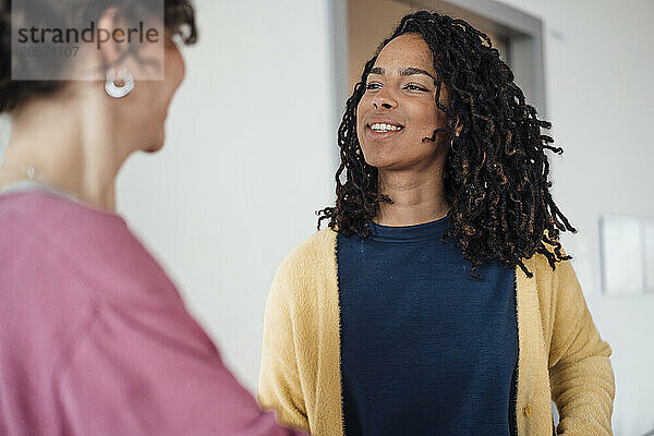 Confident smiling young businesswoman discussing with colleague at office