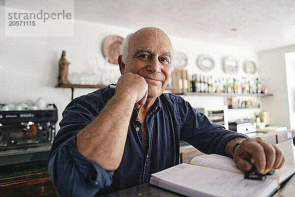 Happy coffee shop owner with diary at cafe