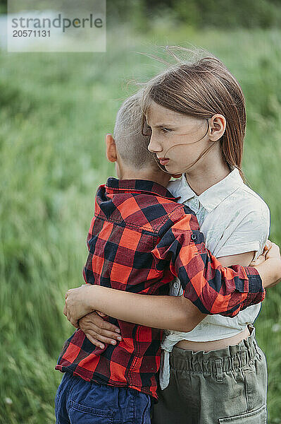 Siblings hugging each other on field