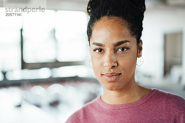 Confident young businesswoman with hair bun at office