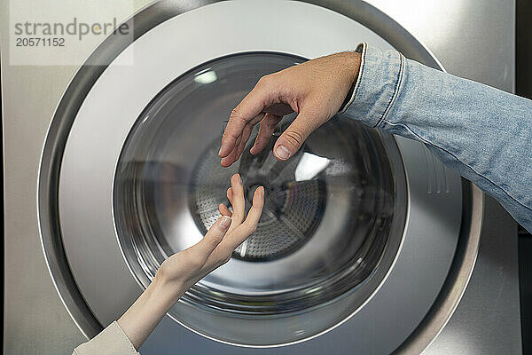 Hands of couple reaching for each other in laundromat