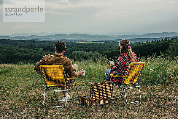 Young couple sitting on chair and looking at view on mountain in Poland