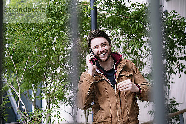 Happy man talking on smart phone at street