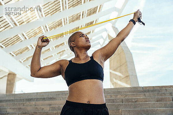 Sporty muscular woman exercising with resistance band