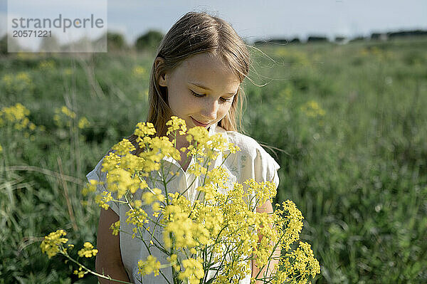 Girl holding bunch of flowers and standing in field