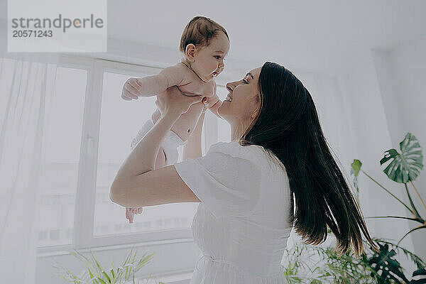 cheerful mother holding baby at home