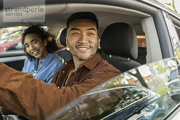 Smiling young man sitting with girlfriend in car