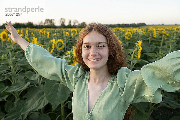 Teenage girl with red hair in sunflowers field