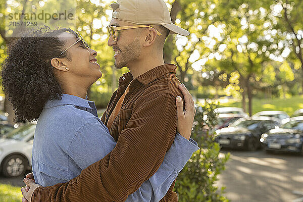 Happy man wearing sunglasses and spending leisure time with girlfriend at park