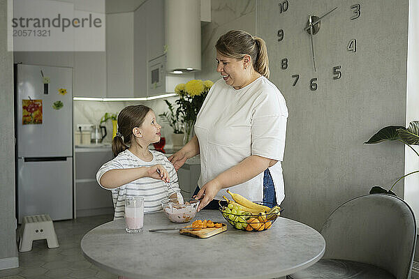 Daughter preparing fruit salad in kitchen at home