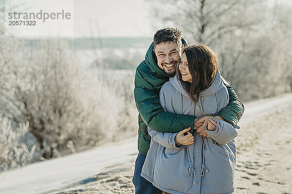 Happy couple embracing each other in winter forest