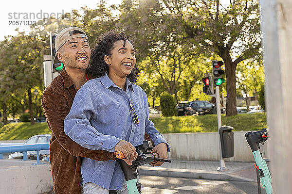 Happy young couple riding electric push scooter at park