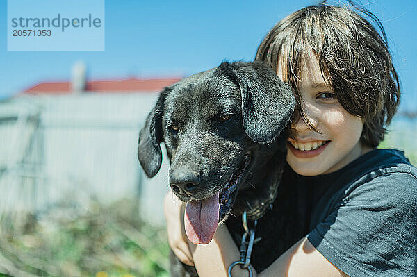 Smiling boy hugging dog in garden